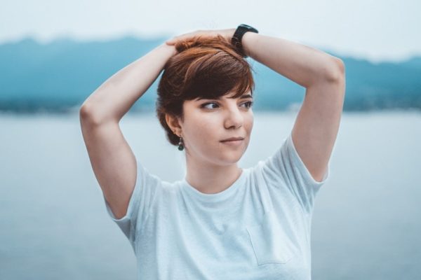 woman in white crew neck t-shirt holding her hair