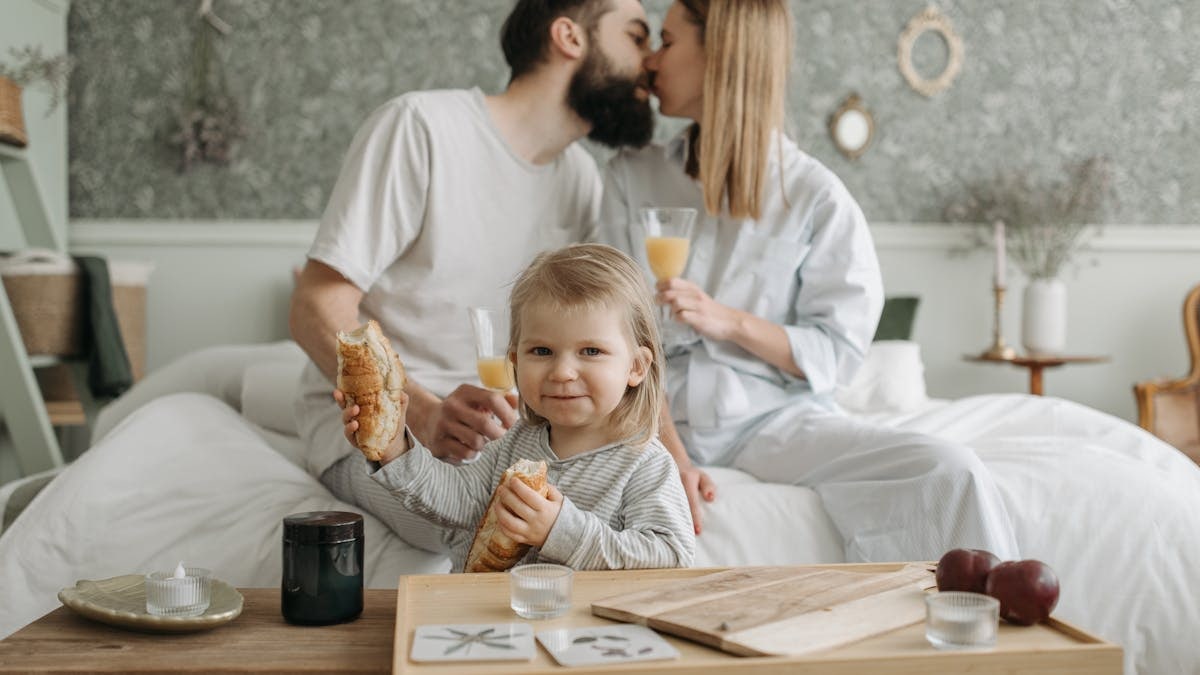 Family enjoying breakfast in bed, expressing love and togetherness.